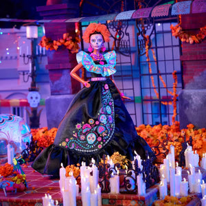 Barbie Día de Muertos 2024 collectible doll displayed in festive altar-inspired scene with candles and marigold decorations.