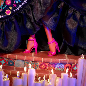 Close-up of Barbie Día de Muertos 2024 doll wearing bright pink high heels under a black embroidered dress.