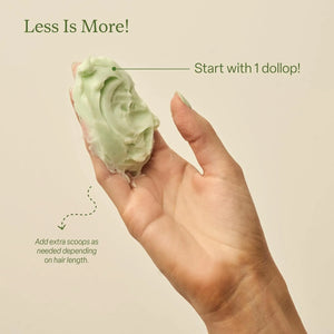 Hand holding a dollop of Divi Whipped Repair Hair Treatment Mask showing light, airy texture and recommended single scoop usage.