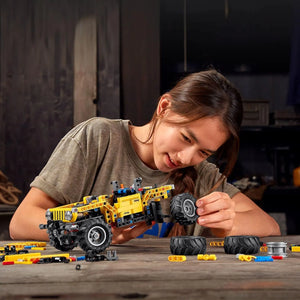 Child assembling LEGO Technic Jeep Wrangler 42122 with detachable wheels and building components on table
