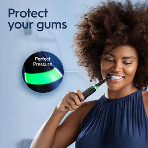 Woman using Oral-B iO Series 3 electric toothbrush showing gum pressure sensor light indicator.