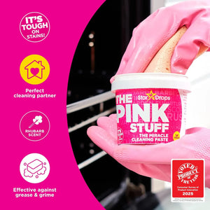 Hand holding Stardrops The Pink Stuff Miracle Cleaning Paste container with rhubarb scent label visible.