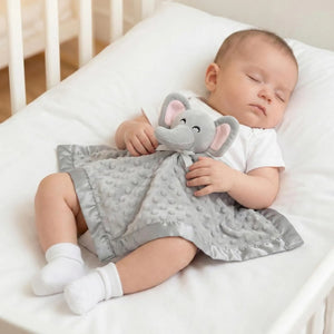 Baby holding Pro Goleem grey elephant security blanket while lying in crib