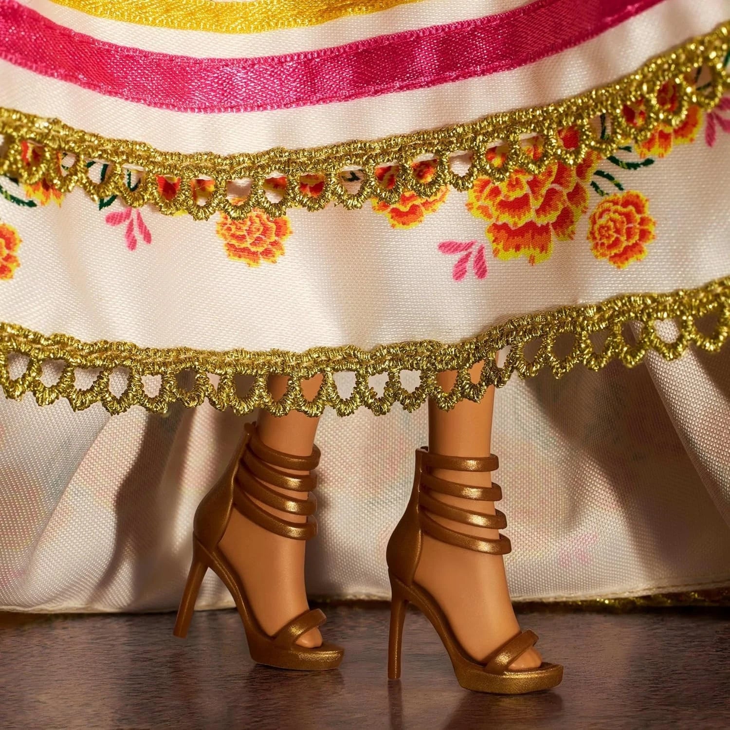Close-up of Barbie Día de Muertos 2025 doll gold heels and ruffled cream gown with marigold embroidery