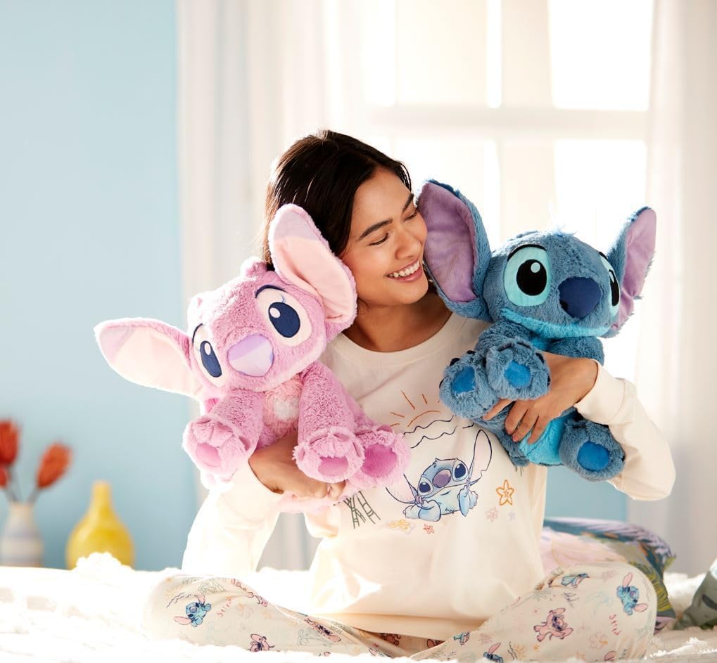 Woman holding Disney Angel and Stitch plush toys indoors, showing medium-sized cuddly characters with soft fuzzy texture.
