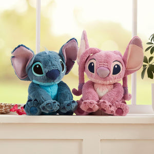 Disney Angel and Stitch medium plush toys sitting side by side near a window, featuring soft fabric and embroidered facial details.