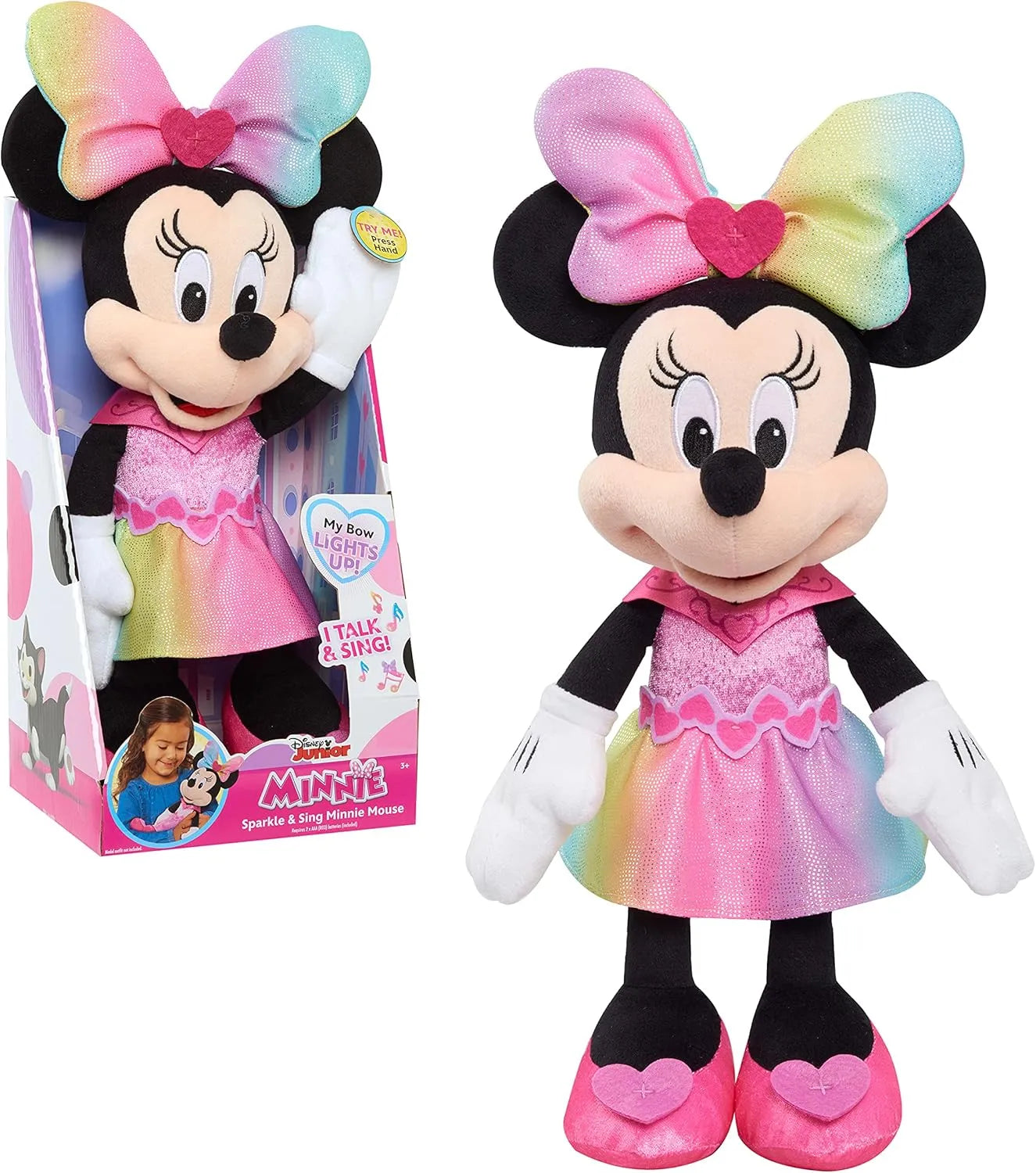 Plush toy of a character with a colorful bow and dress next to its packaging