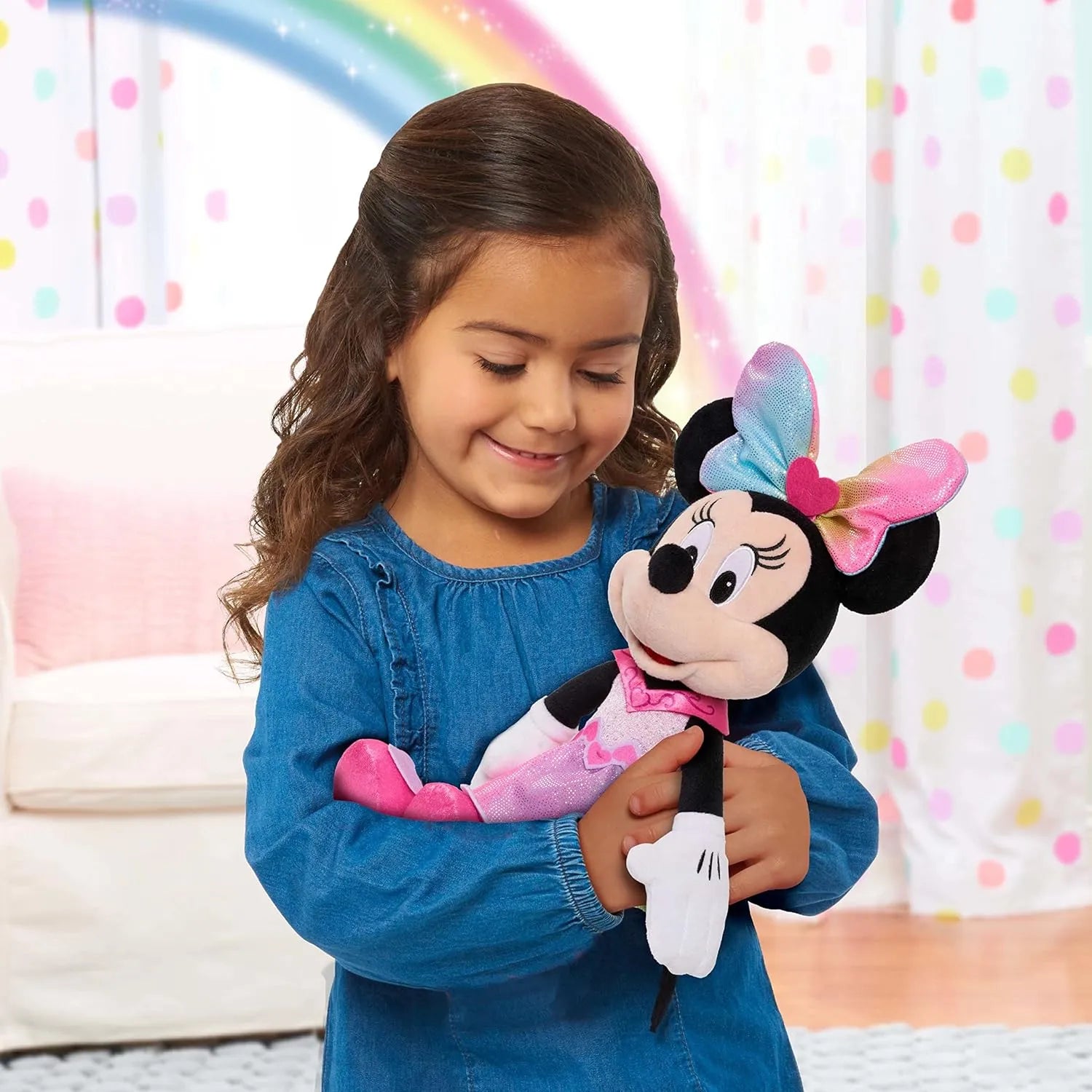 Young girl holding a Minnie Mouse plush toy with a colorful polka dot curtain in the background