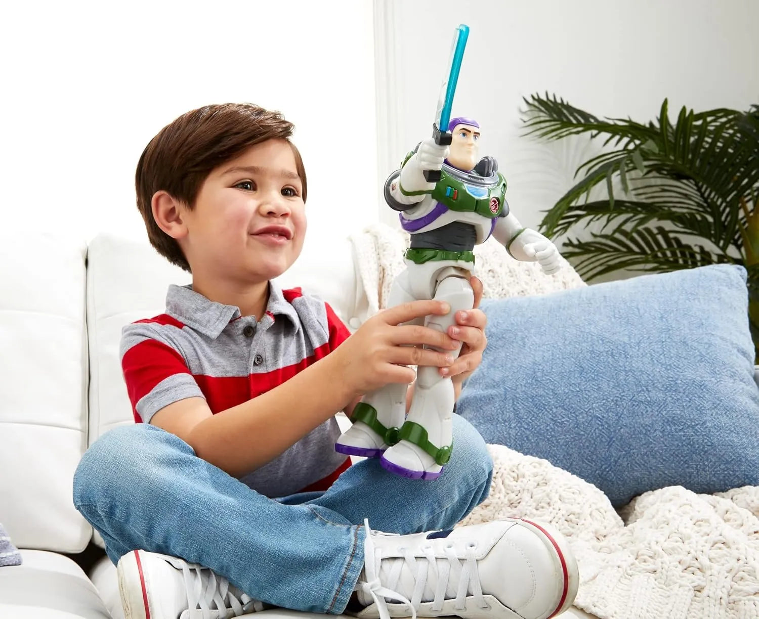 Child holding a Buzz Lightyear toy on a couch with a plant in the background