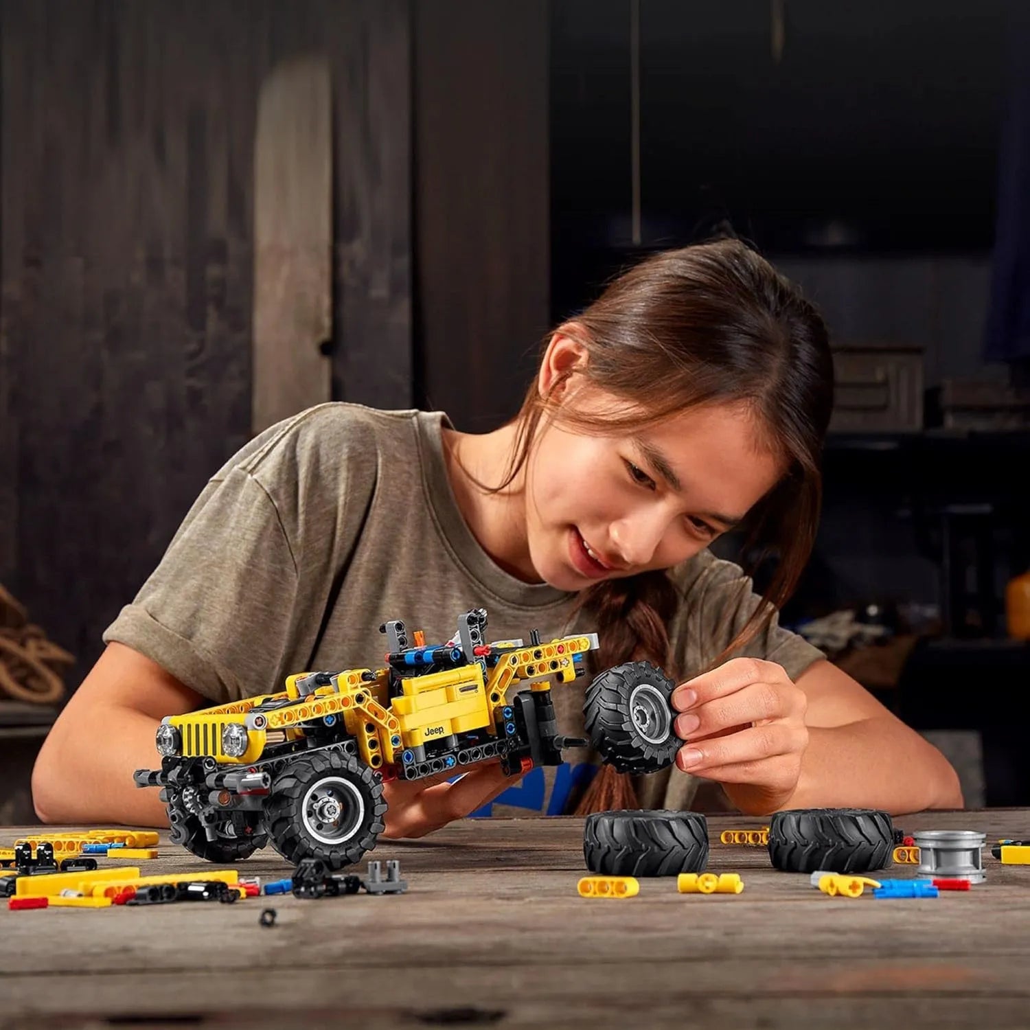 Child assembling LEGO Technic Jeep Wrangler 42122 with detachable wheels and building components on table