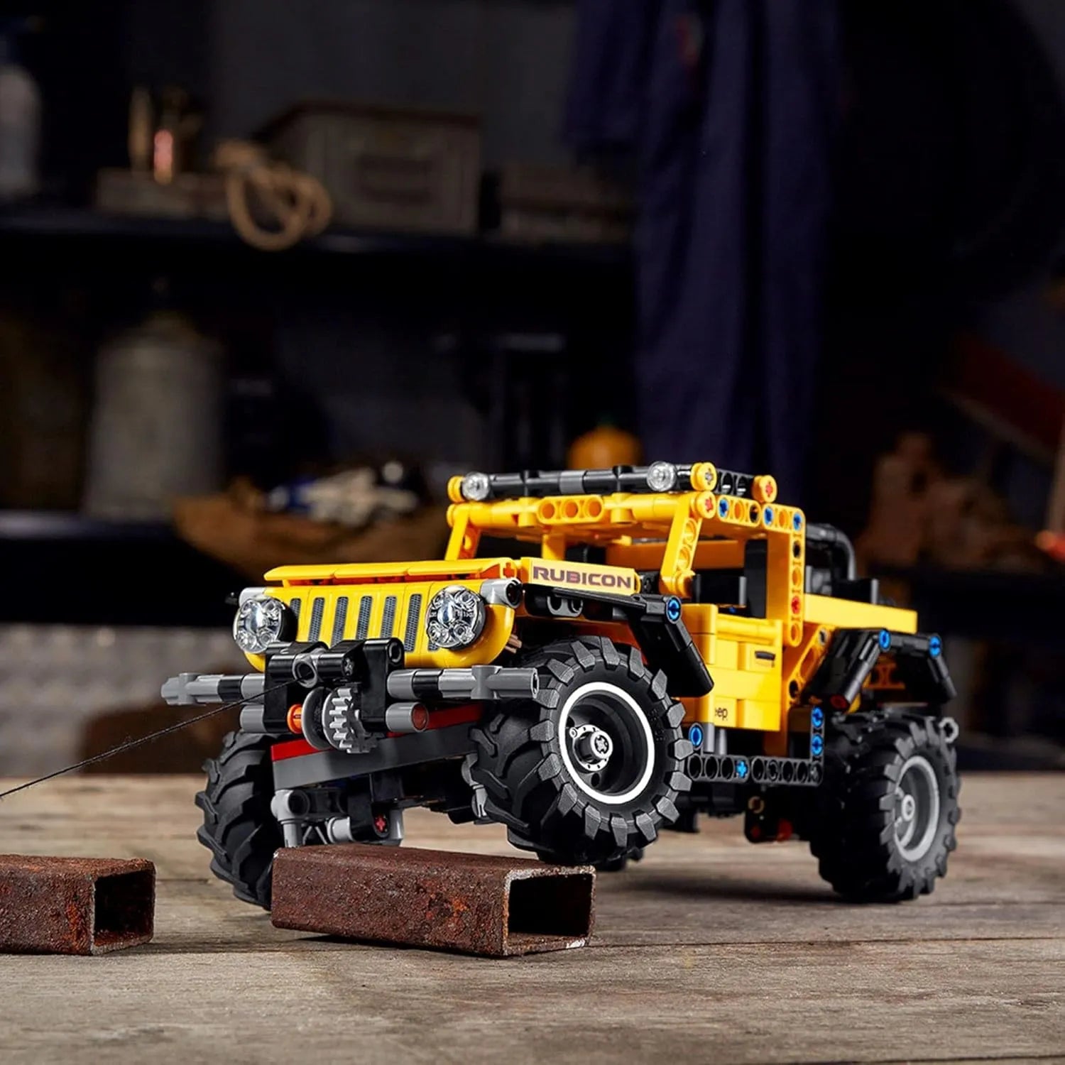 LEGO Technic Jeep Wrangler 42122 model driving over a small obstacle, showing front suspension and off-road tires