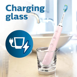 Philips Sonicare DiamondClean 9000 pink electric toothbrush placed in charging glass on bathroom counter.